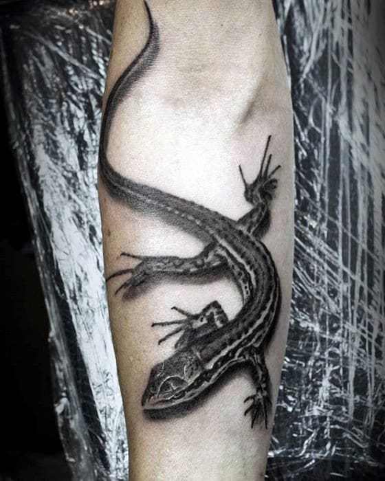 Realistic black and grey gecko tattoo on forearm with detailed stripes, shadow work, and a dynamic crawling position.