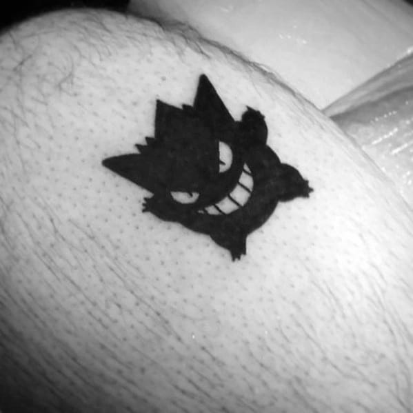 Minimalist black Gengar tattoo with a solid silhouette, wide grin, and white eye details for a simple yet striking design.