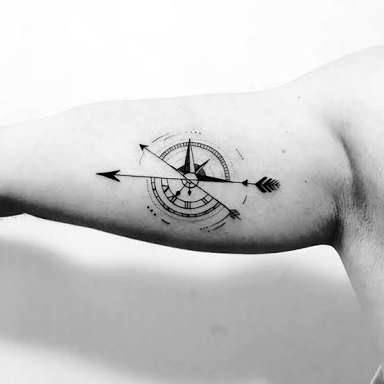 Inner bicep compass tattoo with bold arrow piercing through the center, blending precision with symbolic direction.