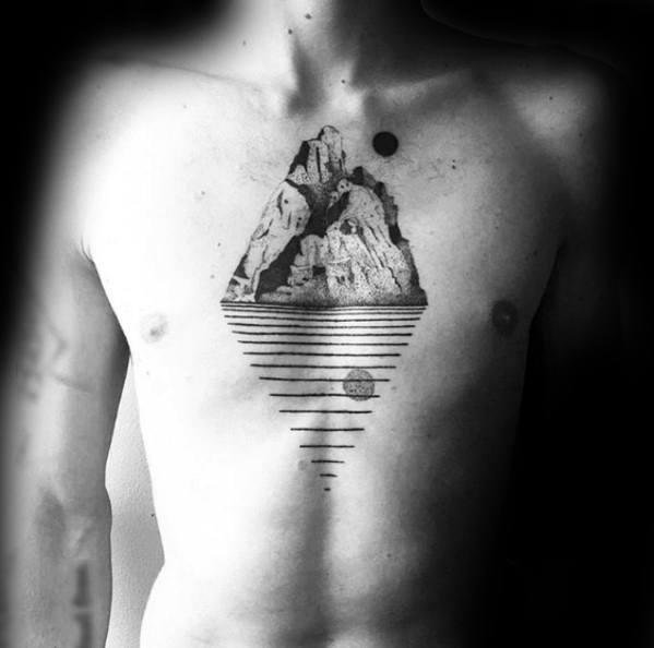 Surreal mountain chest tattoo with bold shading, floating above horizontal lines forming a triangular base, and a small black sun.