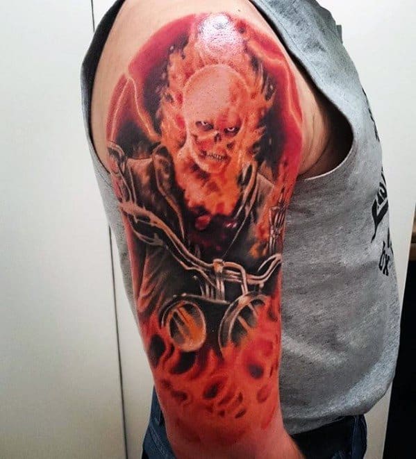 Ghost Rider upper arm tattoo with a fiery skull, intense flames, and detailed motorcycle handlebars in a powerful, blazing composition.