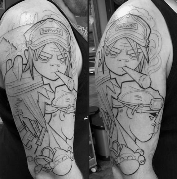 Black linework upper arm tattoo of Gorillaz characters, featuring Noodle smoking with a “Sewage” hat and Murdoc below with detailed outlines.