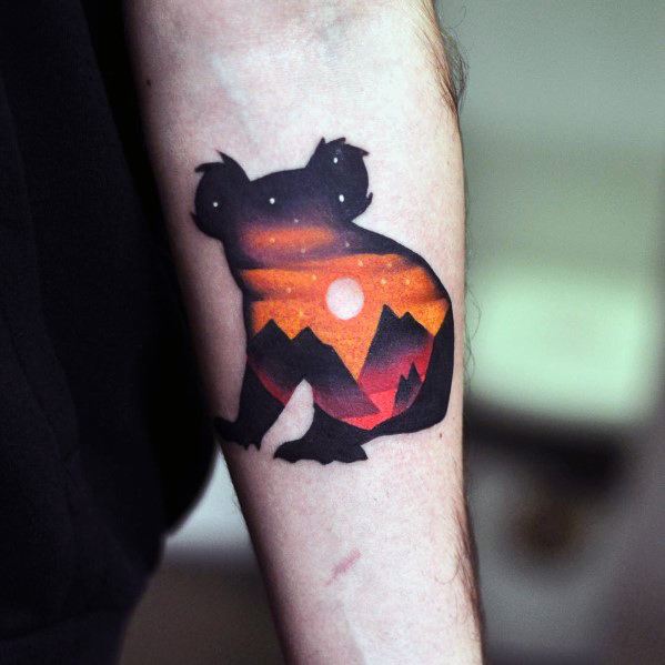 Silhouette tattoo of a koala filled with a sunset mountain landscape, blending orange, red, and black with a glowing sun and stars.