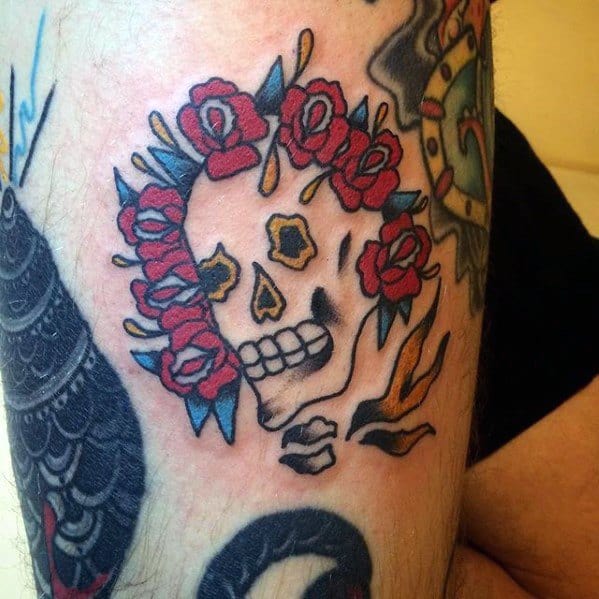 Grateful Dead inspired skull tattoo with a crown of red roses and bold traditional-style lines on the upper leg.