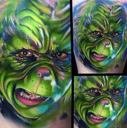 Vibrant and detailed portrait of the Grinch, showcasing his mischievous expression with bold green and yellow hues, creating a dynamic and eye-catching tattoo.