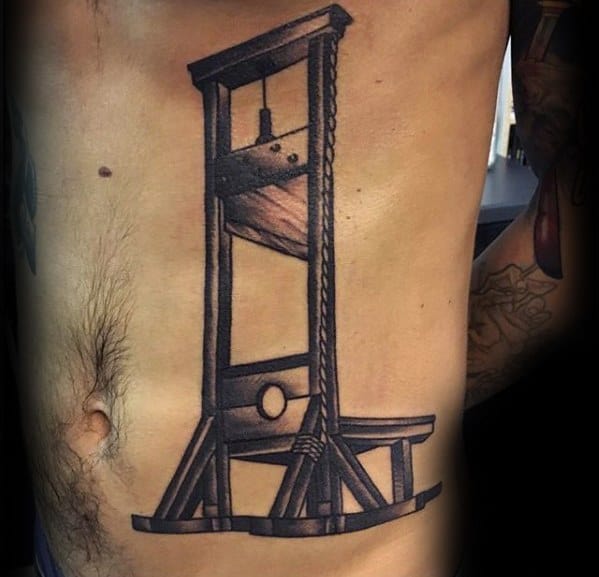Large guillotine tattoo on the ribs with bold black shading, thick rope detail, and strong structural lines for a striking impact.