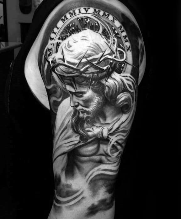 Tattoo of Jesus wearing a crown of thorns with Roman numerals above, detailed in grayscale on an upper arm