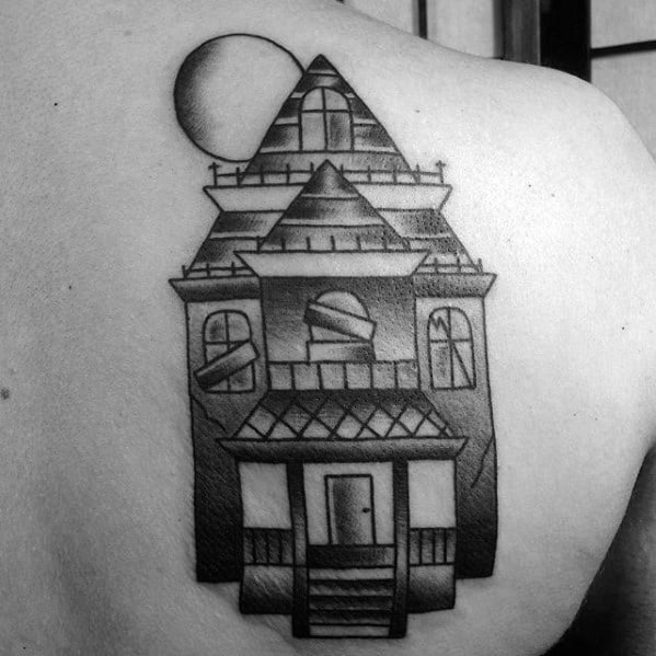Minimalist haunted house tattoo on the shoulder with boarded windows, sharp rooflines, and a shadowed full moon overhead.