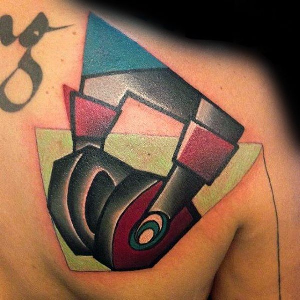 Cubist-style tattoo on the chest featuring abstract geometric headphones in bold shades of black, red, teal, and green.