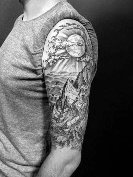 Black and white mountain sleeve tattoo featuring a dramatic full moon, clouds, and rugged peaks, symbolizing adventure and nature’s power.