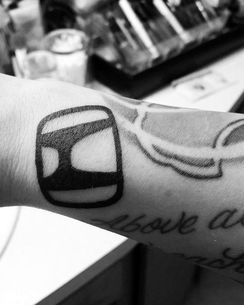 Bold black Honda logo tattoo on a man's wrist, featuring a simple yet striking design with clean lines.