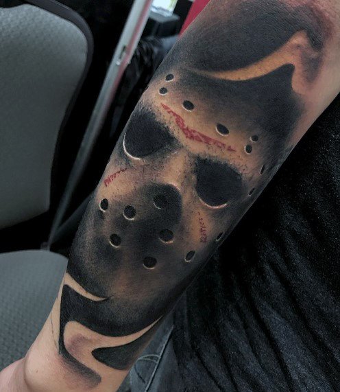 Realistic tattoo of Jason Voorhees' hockey mask from *Friday the 13th*, featuring dark shading, blood splatters, and eerie details for a haunting effect.