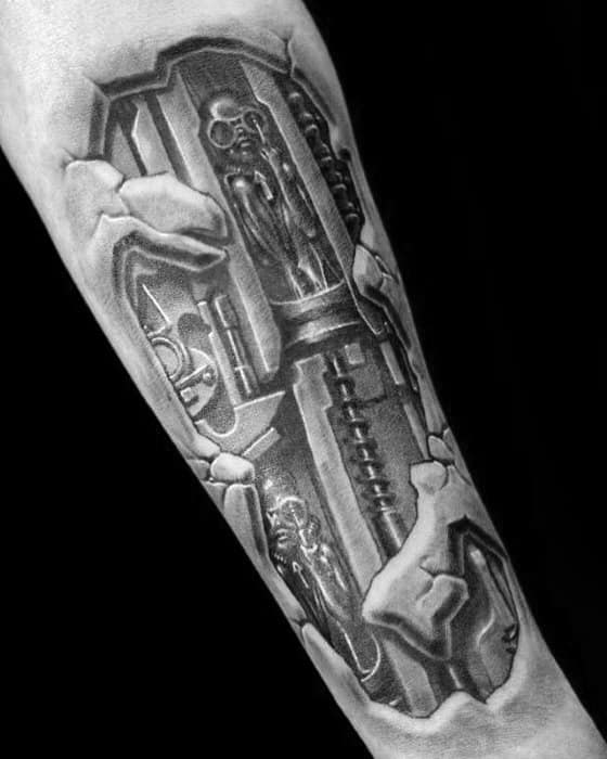 Biomechanical tattoo inspired by HR Giger, showing small alien figures encased in machinery beneath torn skin effect on the forearm.