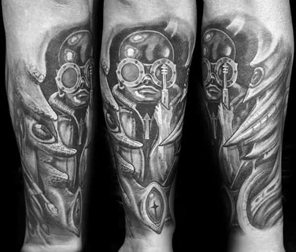 HR Giger-style tattoo featuring eerie alien figures with large goggles and mechanical details, surrounded by surreal organic shapes.
