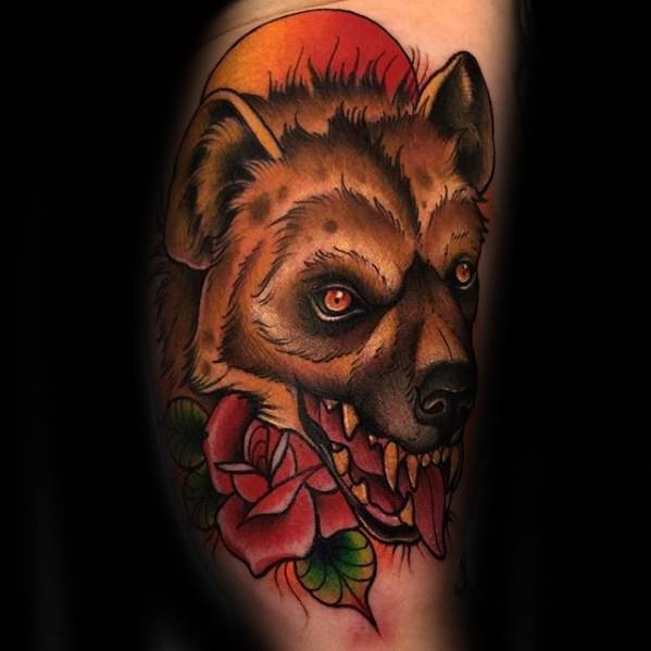 Vibrant hyena head tattoo with glowing red eyes, snarling mouth, a red rose below, and a bold orange sunset in the background.