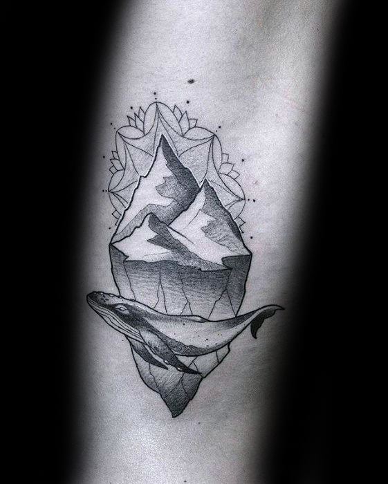 Detailed iceberg tattoo with a swimming whale below and decorative mandala-style elements surrounding the mountain peaks above.