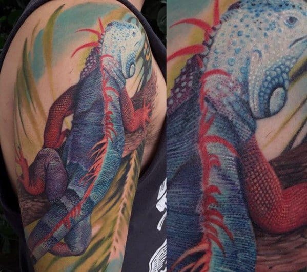 Vibrant iguana tattoo in shades of blue and red with detailed texture, stretching across the upper arm with a dynamic pose.