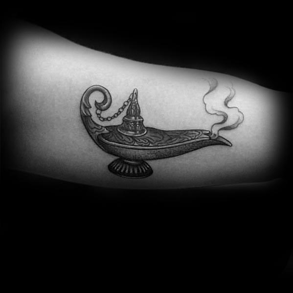 Tattoo of an ornate genie lamp with swirling smoke on a person's arm