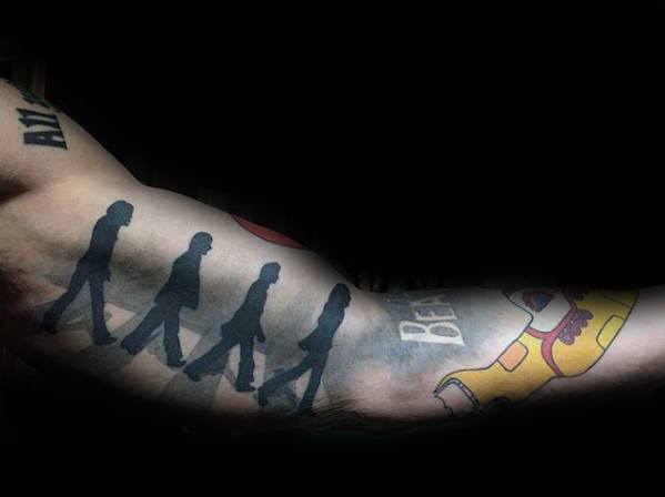 Colorful Beatles tattoo featuring the Abbey Road silhouette in black paired with vibrant Yellow Submarine artwork and "BE" lettering.