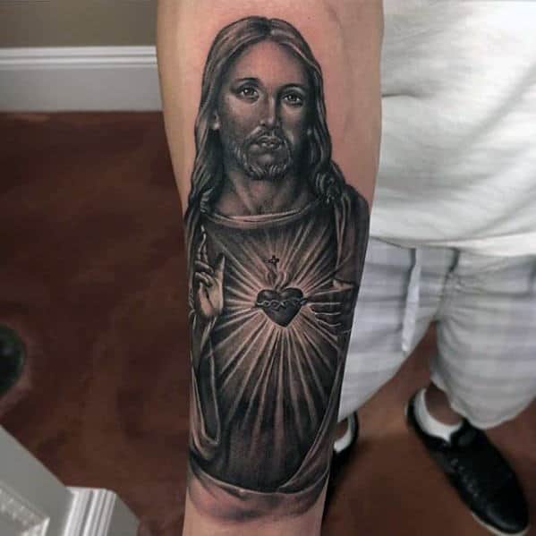 Forearm tattoo of Jesus with the Sacred Heart symbol glowing from his chest