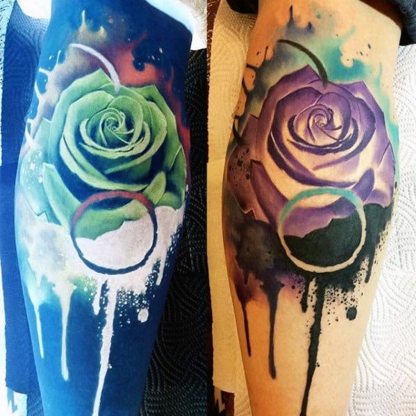 Inverted rose tattoo with watercolor drips, shifting from green and blue hues to purple and tan with a bold circular accent.