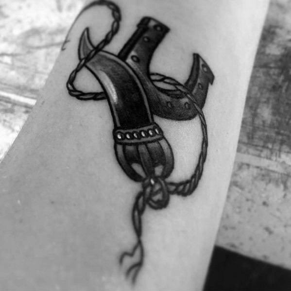Black and grey Italian horn tattoo with a rope and horseshoe, symbolizing luck, strength, and protection.