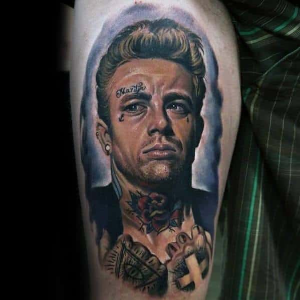 Color tattoo of James Dean reimagined with modern tattoos, a rose on his neck, face ink, and hands clasped in prayer.