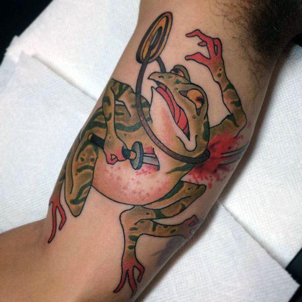 Japanese-style tattoo of a dramatic warrior frog, pierced by a dagger, with intense expression and dynamic pose, symbolizing resilience and sacrifice.