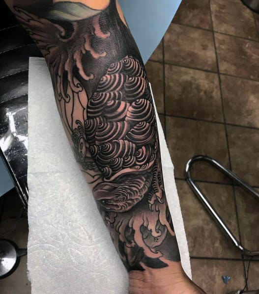 Black and grey Japanese turtle tattoo sleeve with intricate wave patterns, bold shading, and dynamic flow, creating a powerful and timeless design.