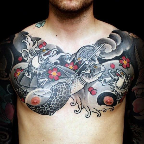Japanese-style chest tattoo featuring a turtle, mythical creatures, cherry blossoms, and flowing waves, blending bold black and grey shading.