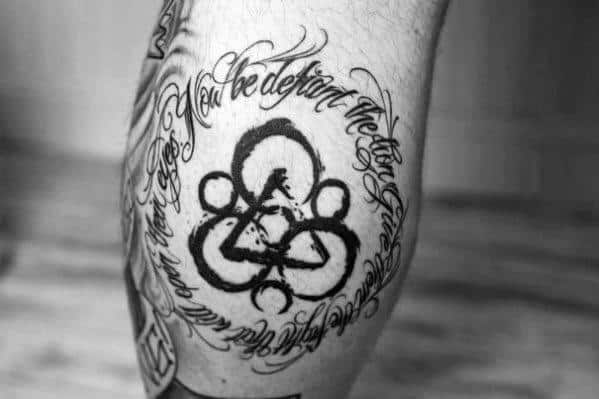 Coheed and Cambria Keywork tattoo with bold black lines, framed by flowing script text in a circular layout for a poetic, personal touch.