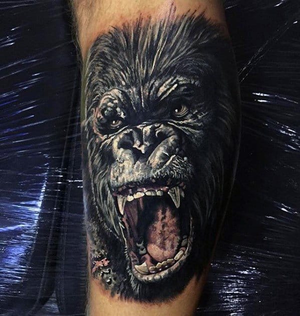 Realistic color King Kong tattoo on leg showing an intense roaring expression with detailed fur, teeth, and lifelike eyes.