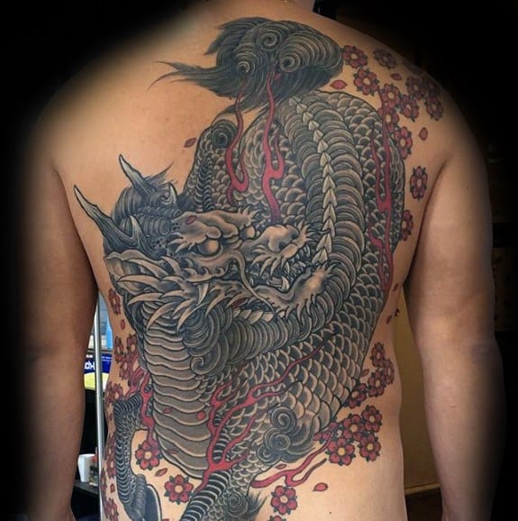 Full-back Kirin tattoo with dark grey scales, red accents, and cherry blossom details creating a fierce yet elegant traditional design.