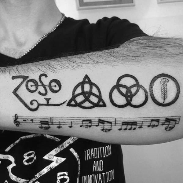 Led Zeppelin tattoo with band member symbols, Zoso emblem, musical notes, and a feather inside a circle on a forearm.