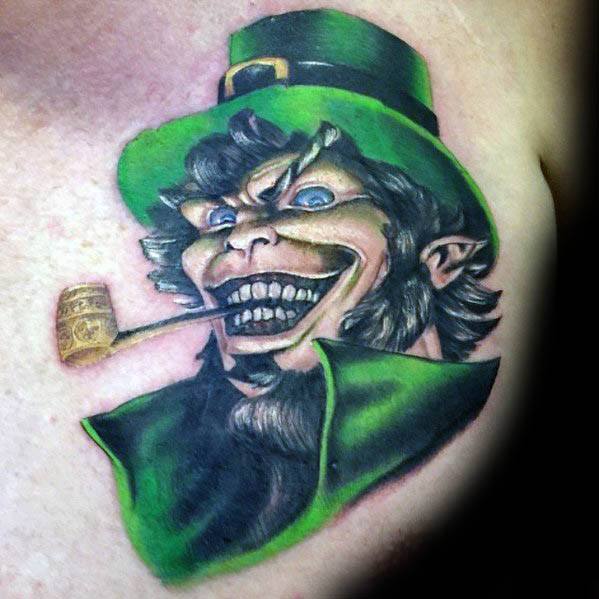 Vibrant tattoo of a crazed leprechaun with wide eyes, sharp teeth, green coat and hat, grinning while holding a smoking pipe in his mouth.