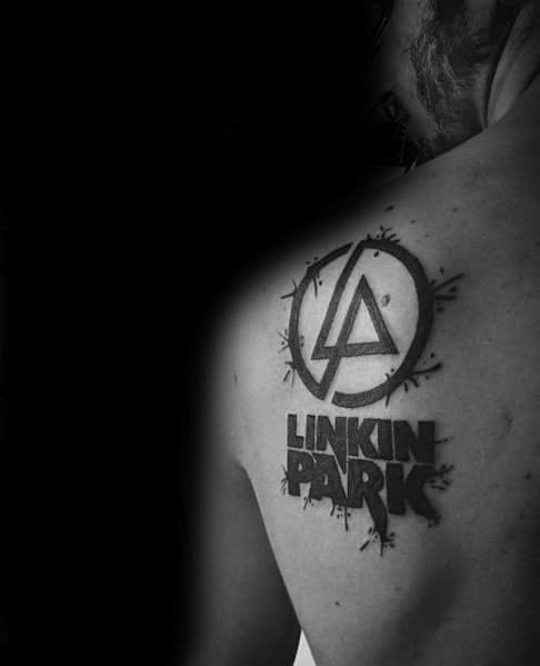 Black ink Linkin Park logo tattoo on the upper back, featuring a bold circular design with grunge-style splatter effects.
