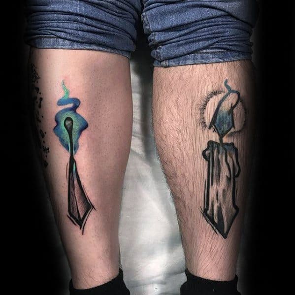 Matching calf tattoos of stylized burning matchsticks—one vibrant with blue and green flame, the other dark and charred—symbolizing contrast between ignition and burnout.