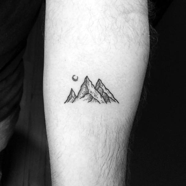 Minimalist mountain tattoo on the forearm, featuring fine line peaks with subtle shading and a small crescent moon for a serene outdoor look.