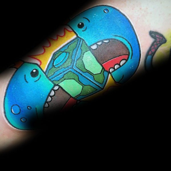 Tattoo of two blue Meeseeks-like creatures biting a glowing green and blue geometric object, with a fiery background.