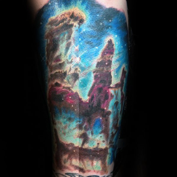 Nebula tattoo featuring vibrant blues, pinks, and starry details set against a dark cosmic backdrop