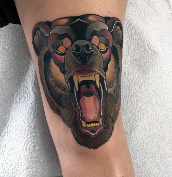 Neo-traditional bear tattoo on the thigh featuring a roaring bear with bold shading, intense orange eyes, and detailed fur texture.