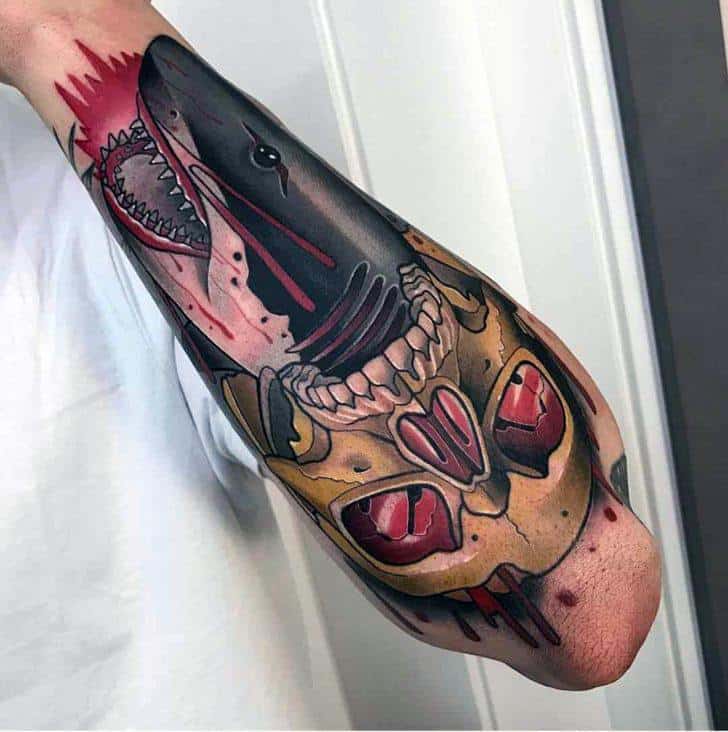 Neo-traditional shark tattoo bursting through a skull with bold red accents, sharp teeth, and dramatic shading on the forearm.