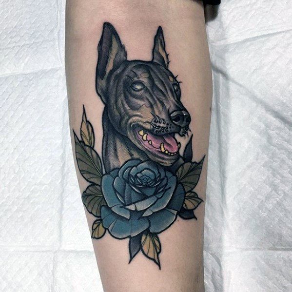 Neo-traditional Doberman tattoo with clean lines, a blue rose, and leaf accents, blending elegance with a fierce expression.