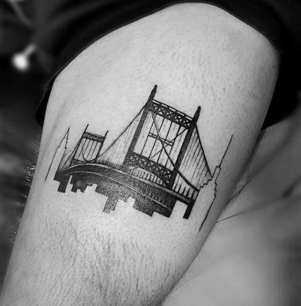 Black ink tattoo of a New York City bridge with a skyline silhouette beneath and iconic buildings like the Empire State Building on the sides.