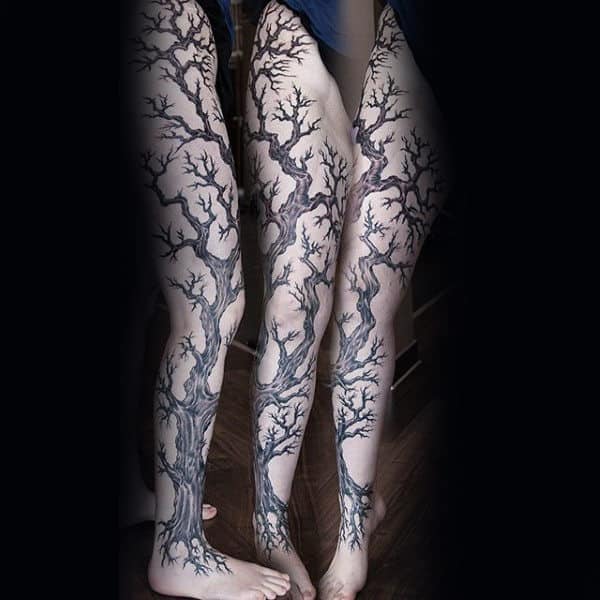 Black and grey full-leg tattoo of intertwining, leafless tree branches, creating a striking and organic design that flows seamlessly with the body.