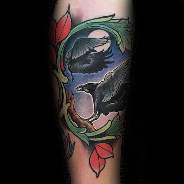 Colorful tattoo of Huginn and Muninn with vibrant leaves and a sky-blue background, framed in bold neo-traditional style on the leg.