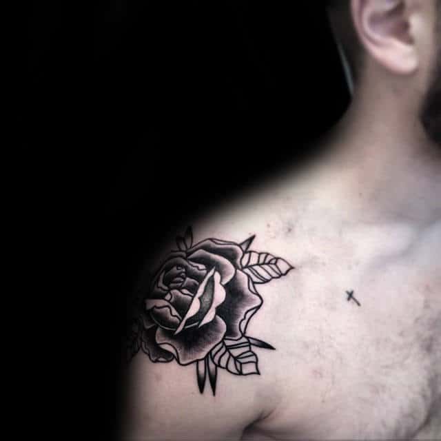 Rose tattoo on a man's shoulder with a small cross tattoo on his chest