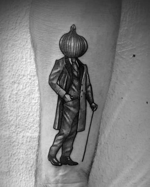 Surreal black and grey tattoo of a gentleman in a suit with an onion for a head, holding a cane, blending vintage aesthetics with surrealism.