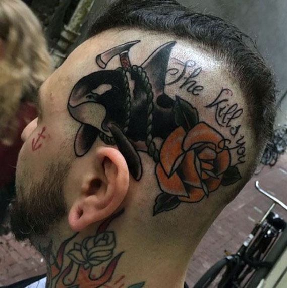 Bold tattoo on the side of the head, featuring an orca whale with a rope and anchor, paired with an orange rose and the text "She Kills You," creating a powerful and striking visual.
