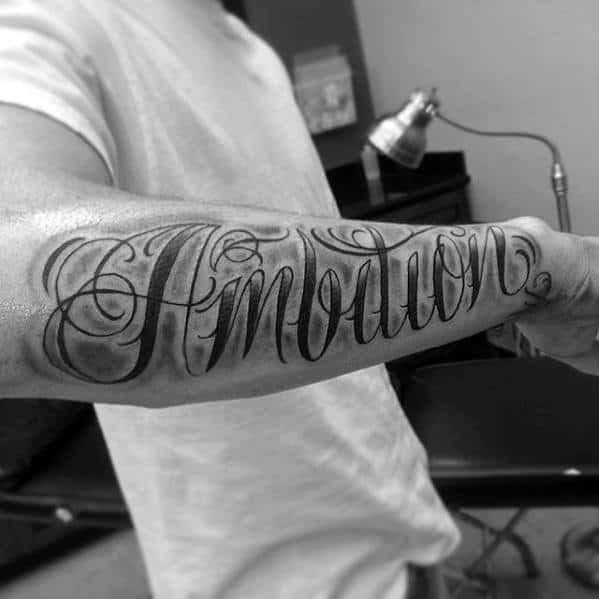 Tattooed forearm with "Emotion" and "Ambition" elegantly scripted in black ink